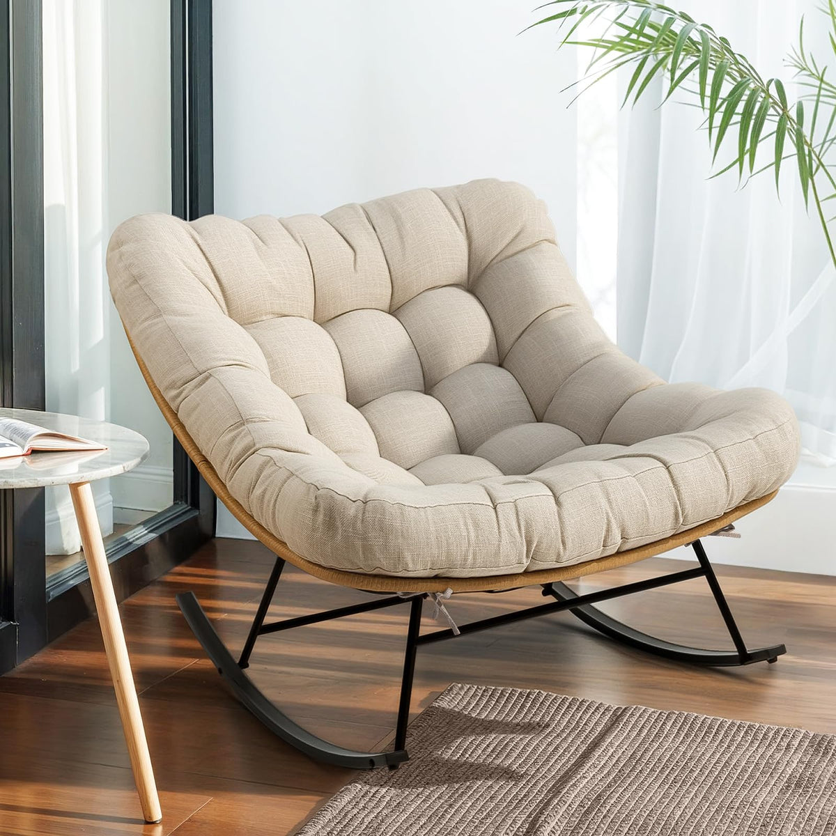 Metal moon rocking chair with beige cushion and black matte frame for indoor reading